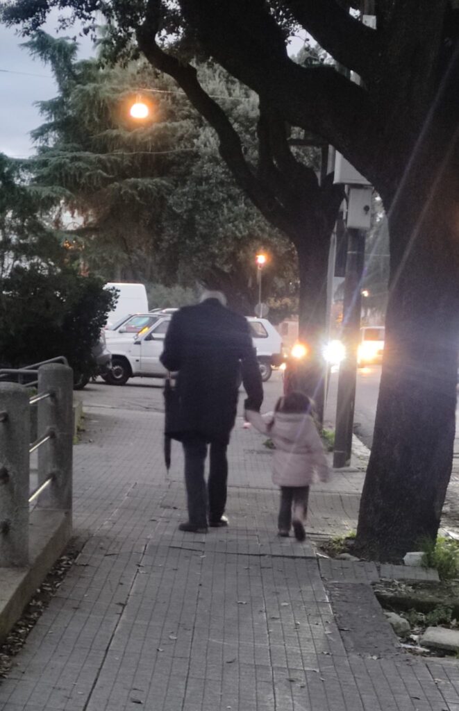 Un anziano e una bambina passeggiano insieme al tramonto